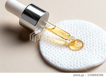 Serum dropper with yellow liquid on cotton pad for skincare routine or beauty treatment Serum dropper with yellow liquid on cotton pad for skincare routine or beauty treatment 134669346