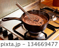Steaming hot chocolate in cast iron pot with whisk on stove 134669477