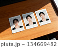 Portrait collection of three passport photos on wooden desk for identification or documentation 134669482