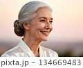 Serene elderly woman smiling against sunset background for wellness and happiness concepts 134669483