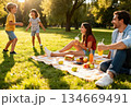 Family enjoying a sunny picnic in the park with young children playing 134669491