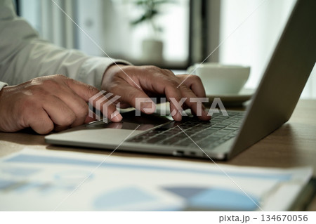 Close up laptop typing hands at office desk laptop work, business working on computer with report documents and data analysis concept Close up laptop typing hands at office desk laptop work, business working on computer with report documents and data analysis concept 134670056