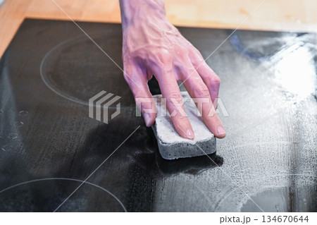 Hand cleaning ceramic cooktop with sponge in modern kitchen Hand cleaning ceramic cooktop with sponge in modern kitchen 134670644