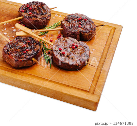 Grilled beef skewers served on a wooden cutting board with herbs 134671398
