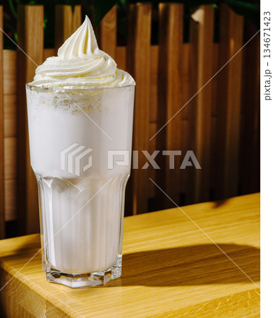 Delicious cold drink topped with whipped cream in a cozy cafe setting Delicious cold drink topped with whipped cream in a cozy cafe setting 134671423