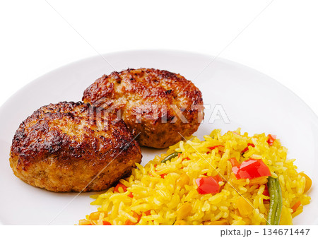 Delicious meat patties served with vibrant yellow rice and vegetables Delicious meat patties served with vibrant yellow rice and vegetables 134671447
