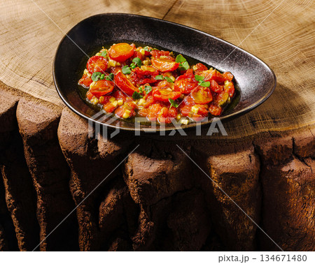 Delicious tomato and vegetable dish served in a stylish bowl on a wooden table Delicious tomato and vegetable dish served in a stylish bowl on a wooden table 134671480