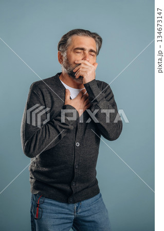 Ill, sick, having pain in the chest. Senior man is standing in the studio against background 134673147