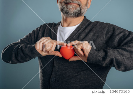 Little heart model in hands. Close up view of senior man against background 134673160