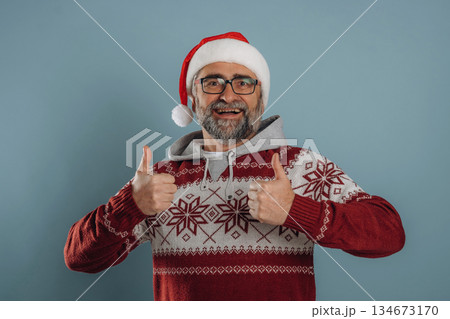 In Santa hat and with gift box. Senior man is standing in the studio against background 134673170