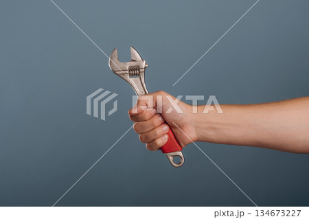 Man's hand holding professional wrench against background 134673227