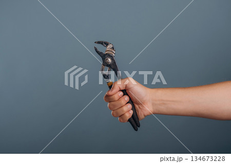 Man's hand holding professional pliers against background 134673228
