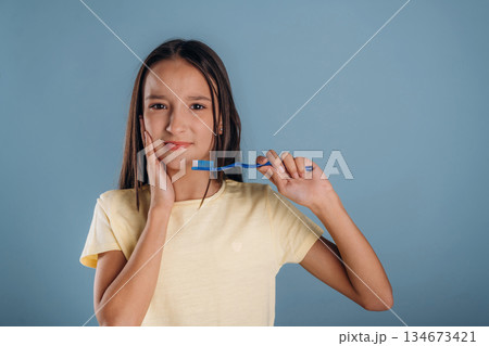 Pain in the tooth, holding toothbrush. Young girl is against background Pain in the tooth, holding toothbrush. Young girl is against background 134673421