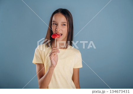 Red sweet candy. Young girl is against background 134673431