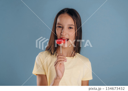 Red sweet candy. Young girl is against background 134673432