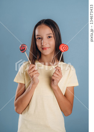Sweet candies. Young girl is against background Sweet candies. Young girl is against background 134673433