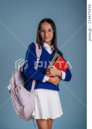 Backpack and books. Young schoolgirl in uniform is against background 134673456
