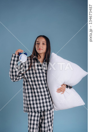 Sleep time, with clock. Young girl in pajama is against background 134673487
