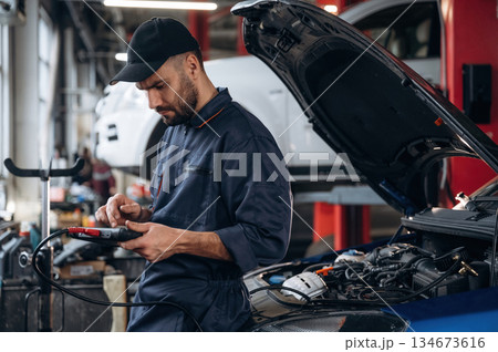 Electronics adjustment, with digital tablet. Mechanic working in a car service station 134673616