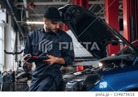 Electronics adjustment, with digital tablet. Mechanic working in a car service station 134673618