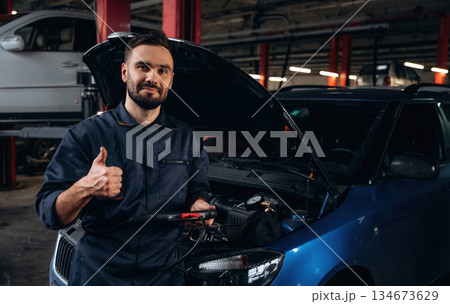 Black digital tablet in hands. Mechanic working in a car service station Black digital tablet in hands. Mechanic working in a car service station 134673629