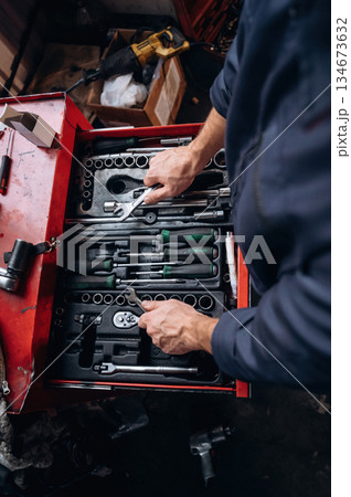 Choosing bunch from bunch of tools. Close up view of mechanic in car service station Choosing bunch from bunch of tools. Close up view of mechanic in car service station 134673632