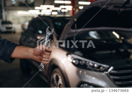 Showing tools, holding in hands. Close up view of mechanic in car service station 134673668