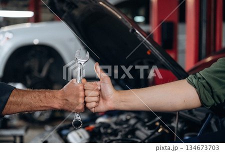Hands of mechanic and client, holding tool, car service station 134673703