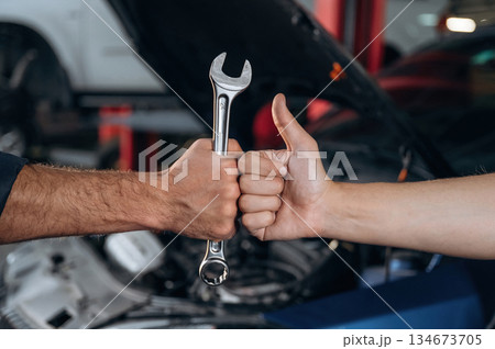 Hands of mechanic and client, holding tool, car service station 134673705