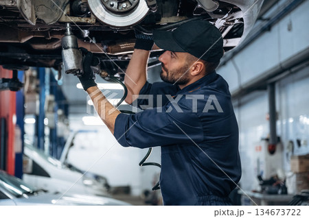 Automobile is up, hanging. Mechanic working in a car service station 134673722