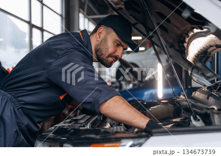 Busy, work is in progress. Mechanic is in a car service station Busy, work is in progress. Mechanic is in a car service station 134673739