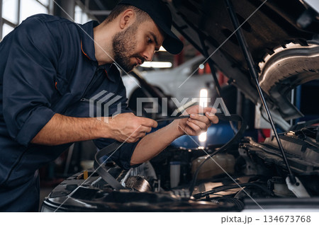 Cable installation. Mechanic working in a car service station Cable installation. Mechanic working in a car service station 134673768