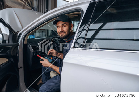Sitting in automobile. Mechanic working in a car service station Sitting in automobile. Mechanic working in a car service station 134673780