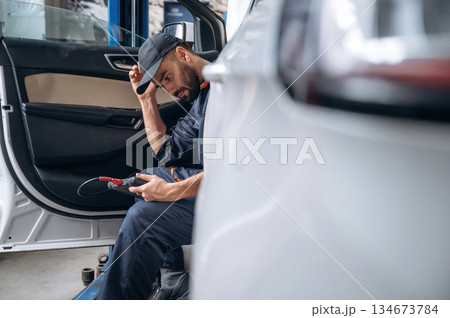 Break time, sitting in automobile. Mechanic working in a car service station 134673784