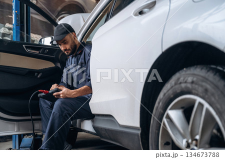 On the seat, with digital tablet. Mechanic working in a car service station On the seat, with digital tablet. Mechanic working in a car service station 134673788