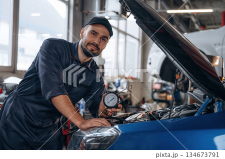 Focused at work. Mechanic is in a car service station Focused at work. Mechanic is in a car service station 134673791