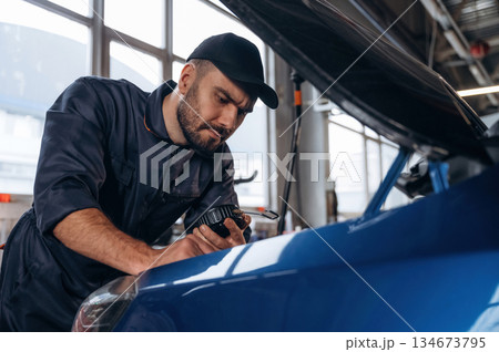 Focused at work. Mechanic is in a car service station Focused at work. Mechanic is in a car service station 134673795