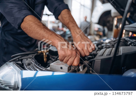 Blue automobile, working. Close up view of mechanic in car service station Blue automobile, working. Close up view of mechanic in car service station 134673797