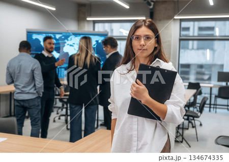 Notepad in hands of woman. Group of office workers are indoors together 134674335