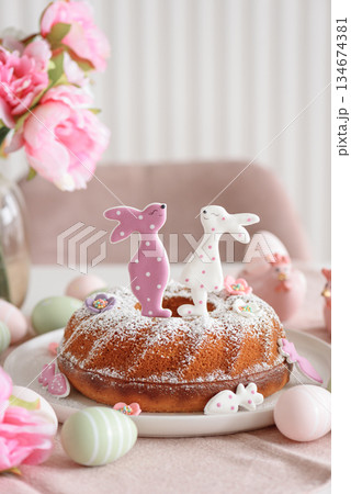 Traditional easter cakes with icing decorated with gingerbread cookies in shape of rabbits on white wooden table Traditional easter cakes with icing decorated with gingerbread cookies in shape of rabbits on white wooden table 134674381