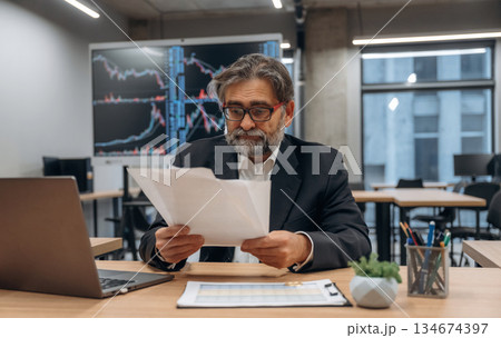 Boring work, sitting by the laptop. Senior man is in the modern office Boring work, sitting by the laptop. Senior man is in the modern office 134674397