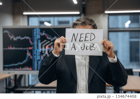In search for a job, holding banner with text. Senior man is in the modern office In search for a job, holding banner with text. Senior man is in the modern office 134674408