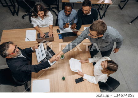 View from the top, by the table. Group of office workers are indoors together 134674858
