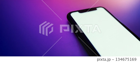 Smartphone with blank white screen lies on bright colorful gradient surface. Smartphone with blank white screen lies on bright colorful gradient surface. 134675169
