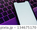Blank white smartphone display on illuminated computer keyboard in neon light 134675170