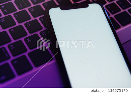 Blank white smartphone display on illuminated computer keyboard in neon light Blank white smartphone display on illuminated computer keyboard in neon light 134675170