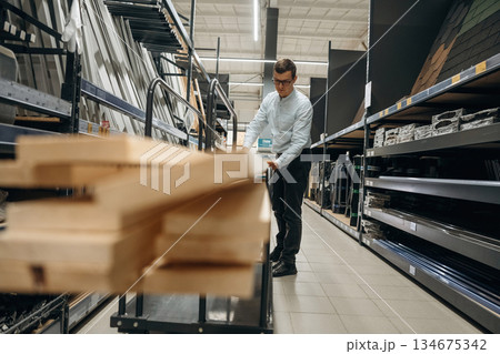 Wooden planks. Male hardware store worker in indoors Wooden planks. Male hardware store worker in indoors 134675342