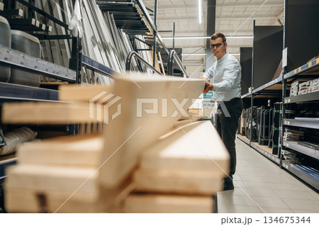 Wooden planks. Male hardware store worker in indoors Wooden planks. Male hardware store worker in indoors 134675344