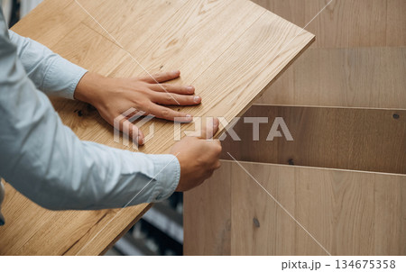 Surface of the parquet. Detailed close up view of man's hand in the hardware store Surface of the parquet. Detailed close up view of man's hand in the hardware store 134675358