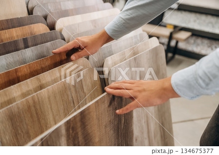 Parquet in different colors. Detailed close up view of man's hand in the hardware store Parquet in different colors. Detailed close up view of man's hand in the hardware store 134675377